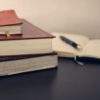 selective focus photography of three books beside opened notebook